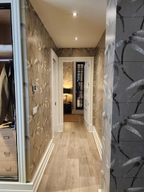 Hallway to bathroom with double sinks and walk in shower, bedroom with king bed