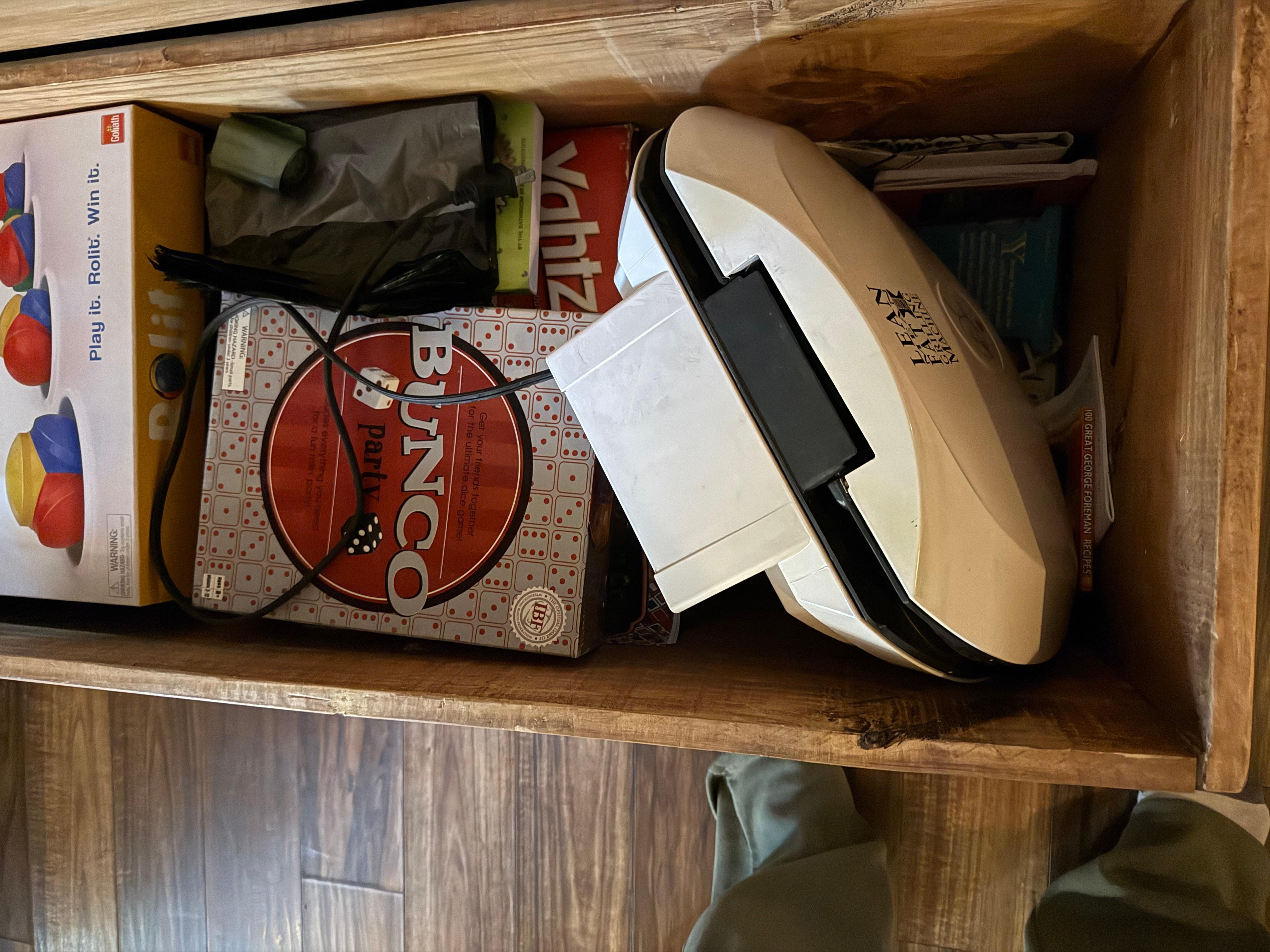 Not sure why a dirty georgeforman grill was not placed in the kitchen that had plenty of space but put with a bunch of board games .