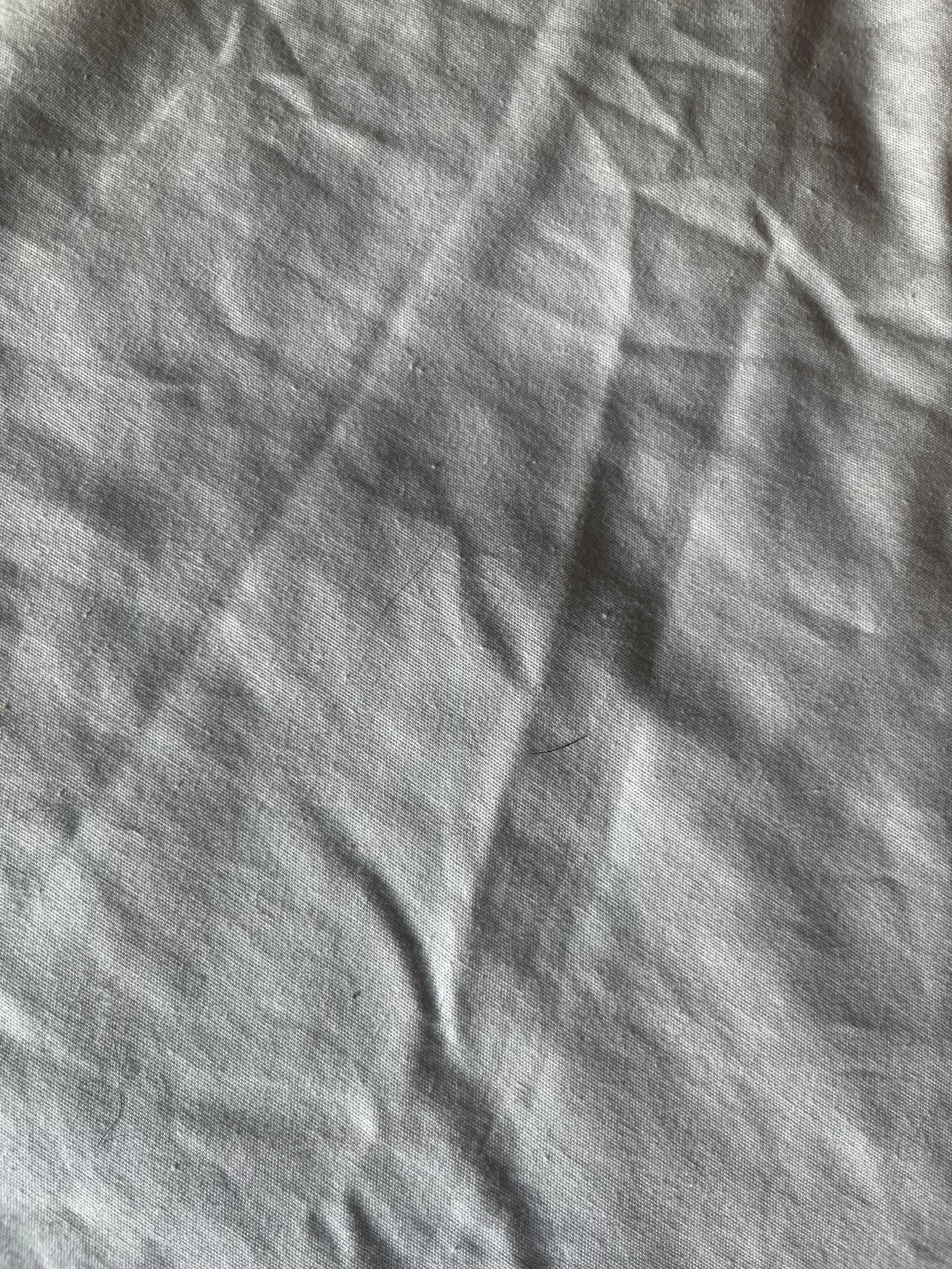 Short dark dog hair and long black curly hair in the bed sheets under the blanket 