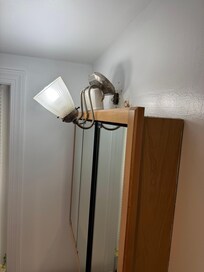 Bathroom light fixture held up by toothbrush holder rendering vanity unusable