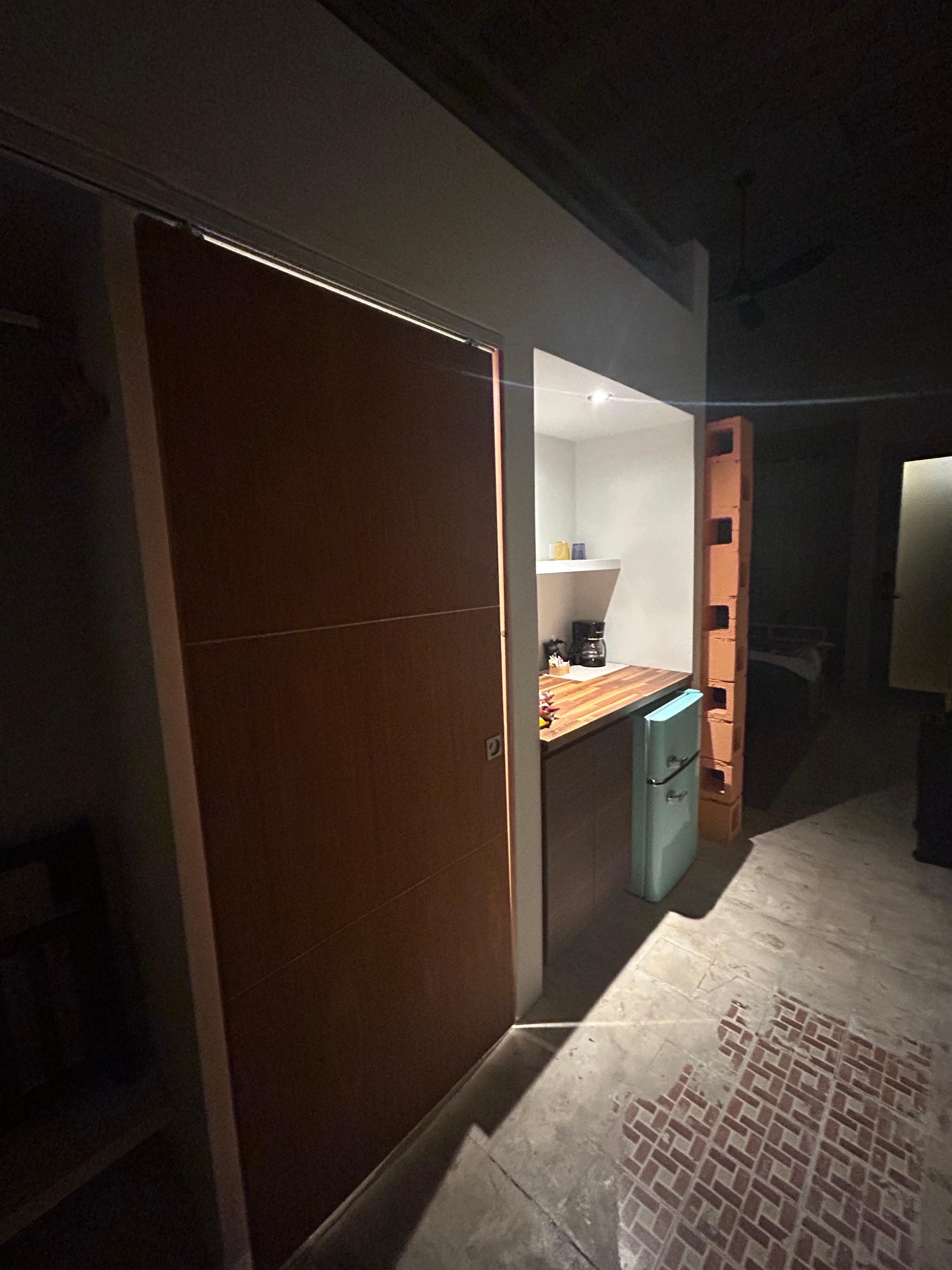 La puerta del baño y donde está la neverita y cafetera y otras cosas,ahí a la parte de arriba está la otra cama la escalera está en el área de la sala para subir allí 