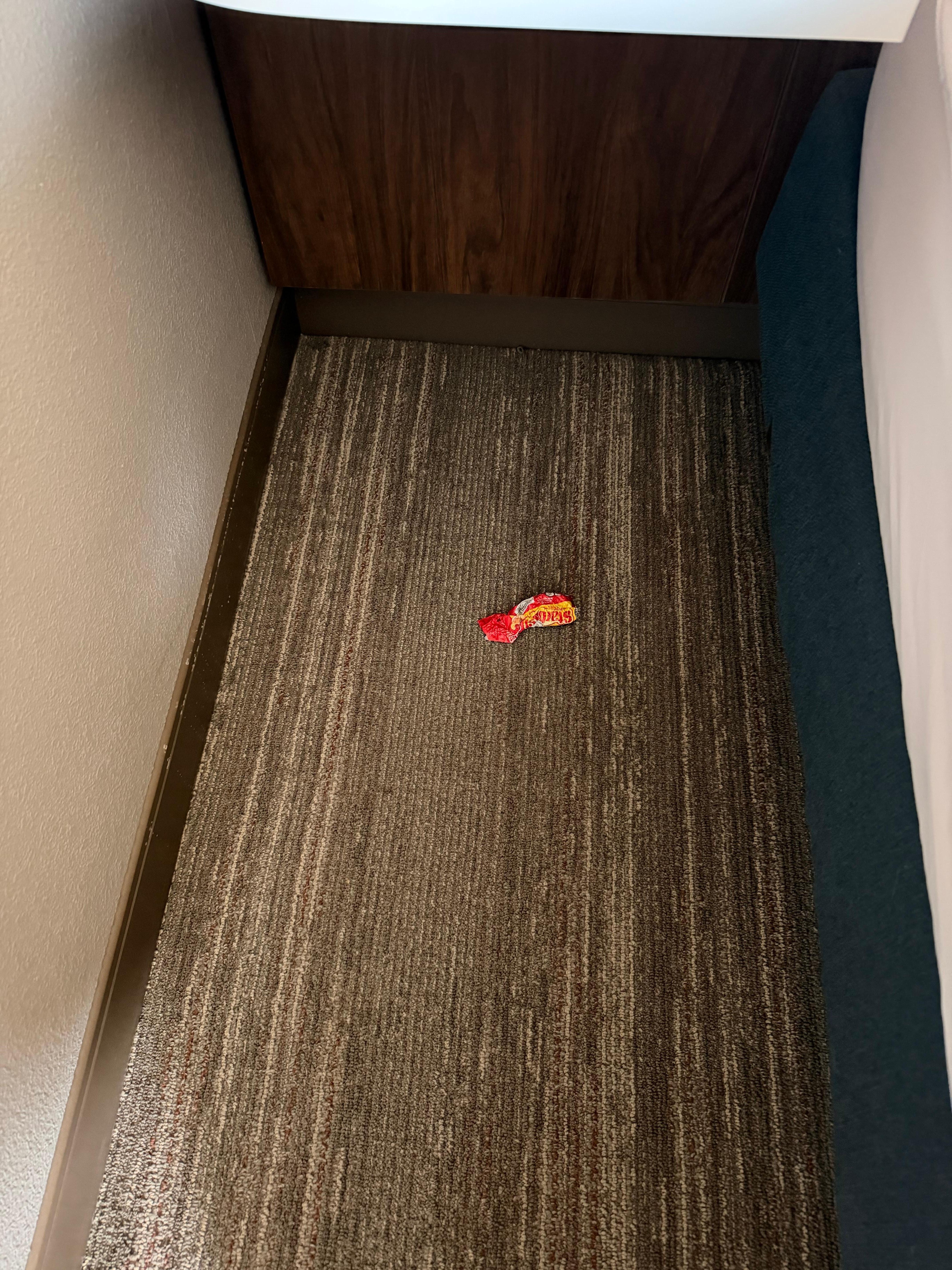 Candy wrapper left along side the bed. 