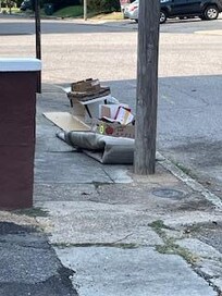 Sketchy area with a pile of junk at the road right next door