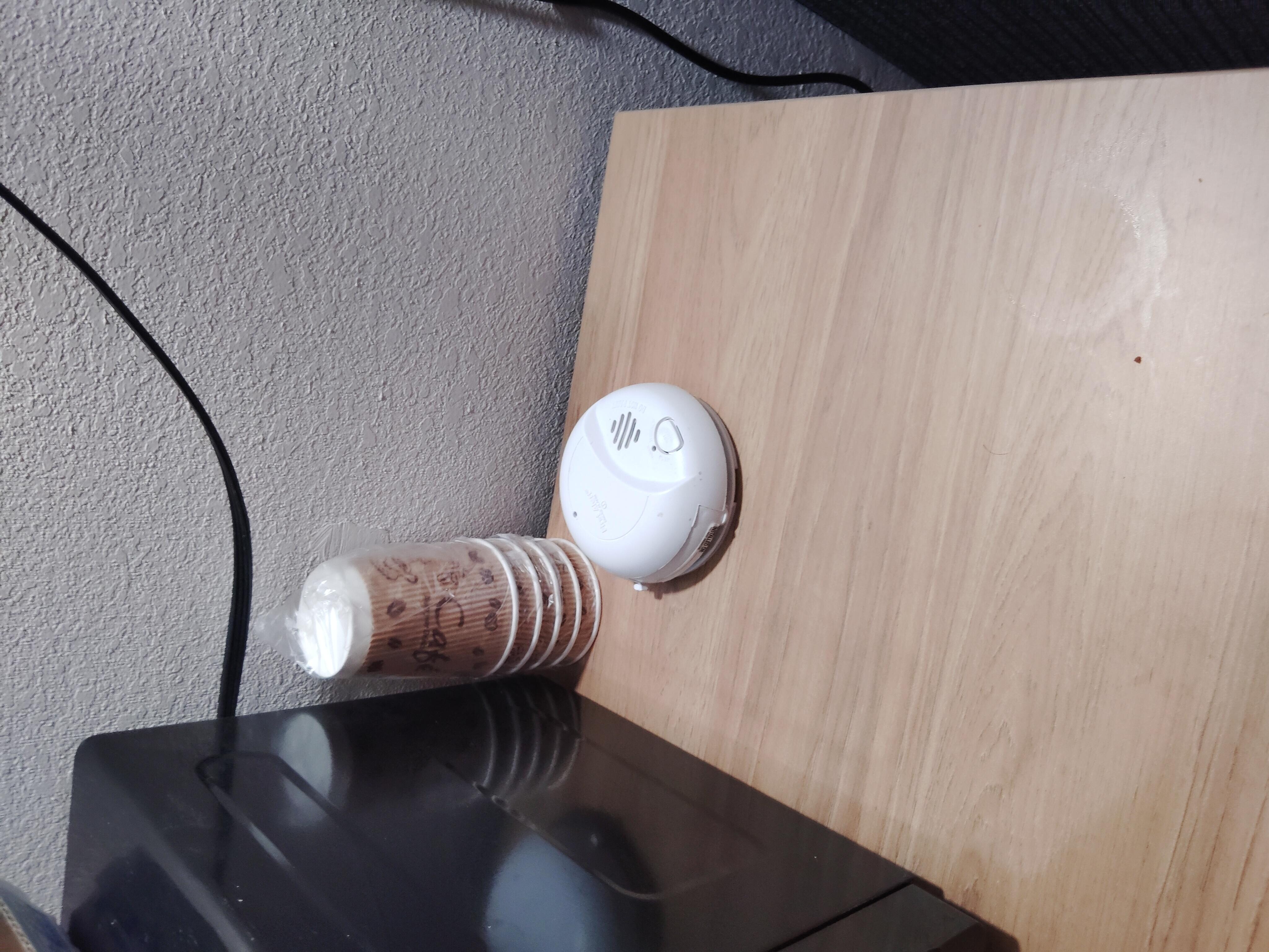 Smoke detector sitting on the table that had the microwave on it.