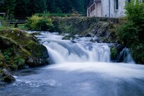 Long exposure of stream alongside house.