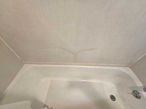 Shower wall cracked, poor attempt at repair.