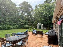 Back deck with seating and grill. Shed and trash container in background