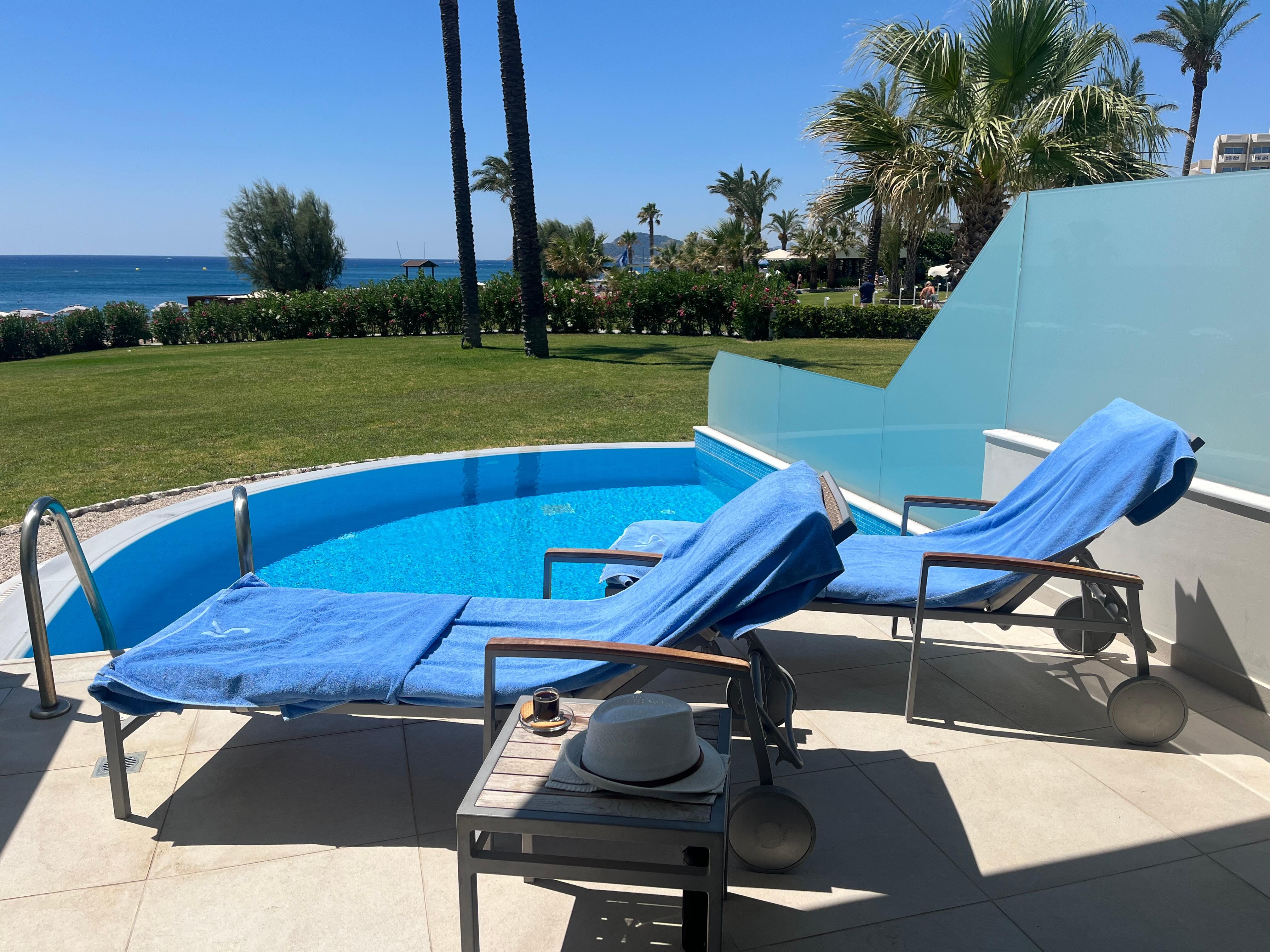 Patio with sun loungers and view of garden and beach. 