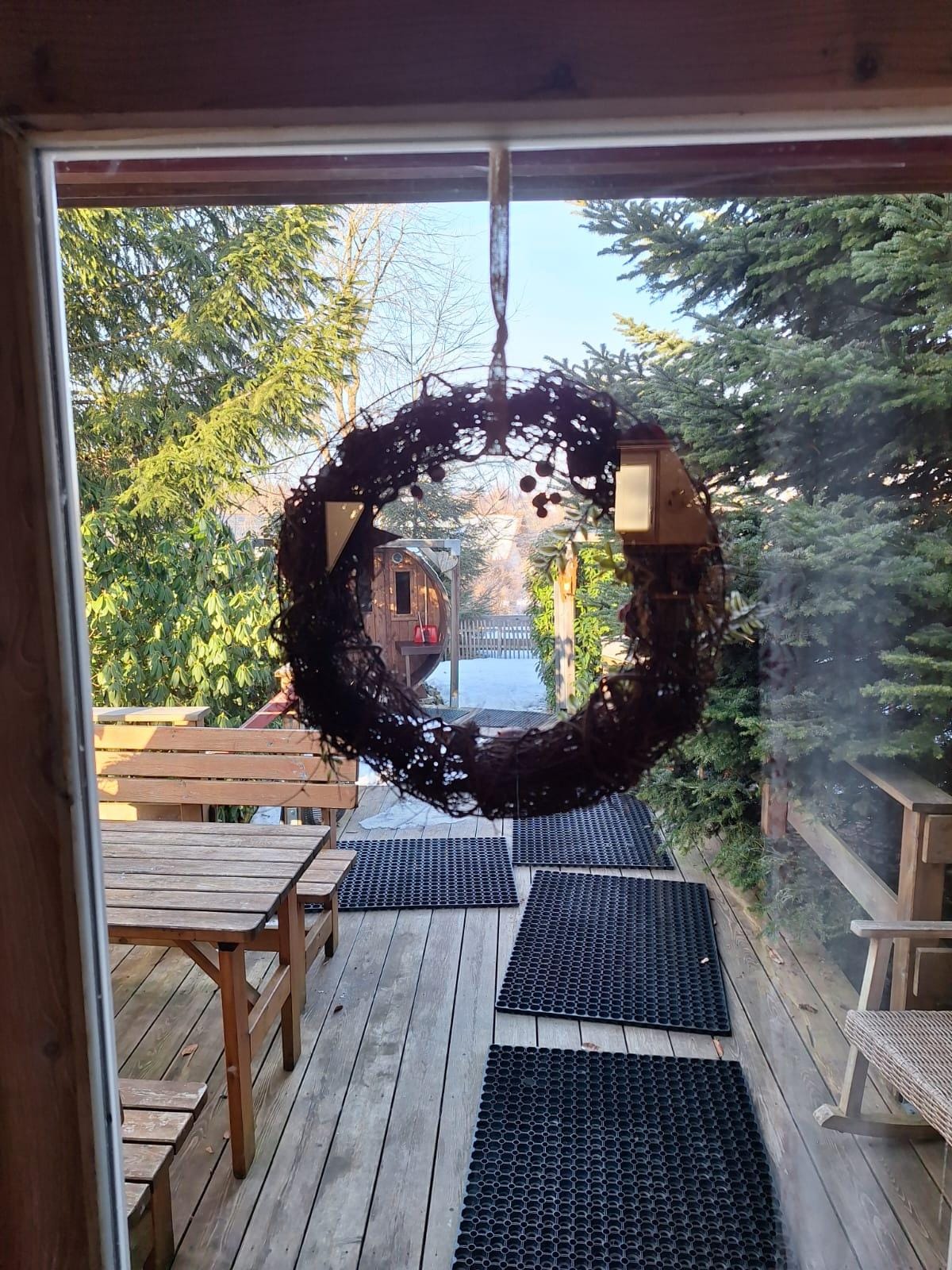 Blick aus der Hütte auf die Sauna (das Fass etwas links) und den Sitzbereich vor der Hütte