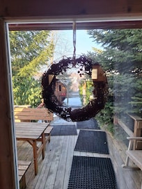 Blick aus der Hütte auf die Sauna (das Fass etwas links) und den Sitzbereich vor der Hütte