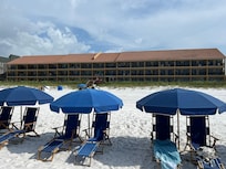 Beach chairs and umbrella with Coral Reef Club in the background.