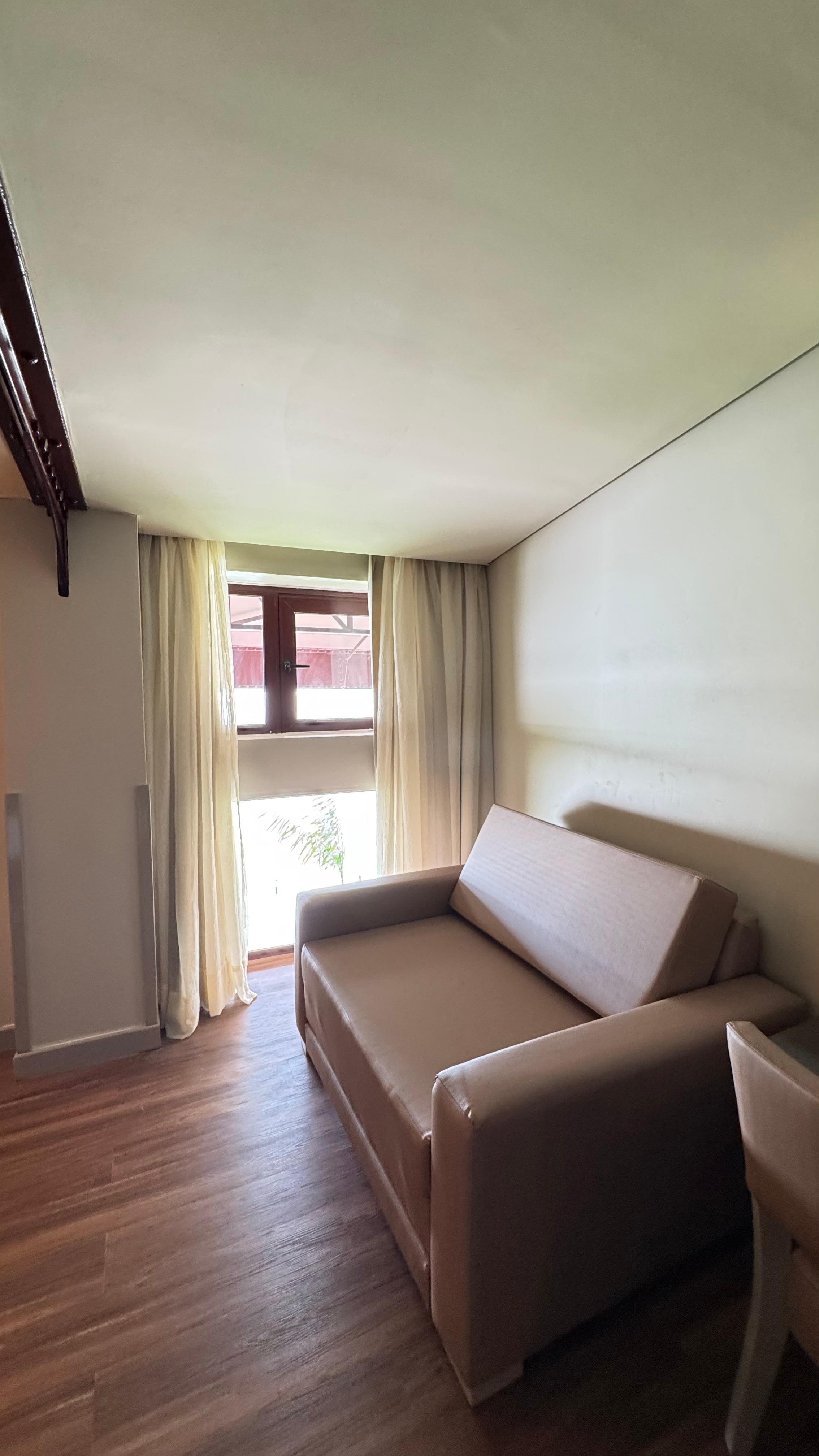Pequena janela com vista e um sofá cama, quando contratei quarto como cama de solteiro