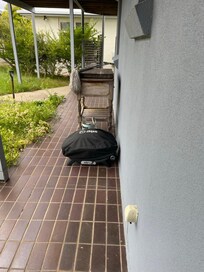 BBQ stored on ground without any practical outdoor furniture for its relocation.