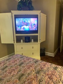 Tv cabinet and tv is Ancient piece of furniture hooked up to an extension cord wired into the ceiling.