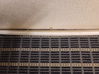 Damaged floor trim on room wall.