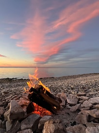 Campfire and sunset on beach in front of cottage