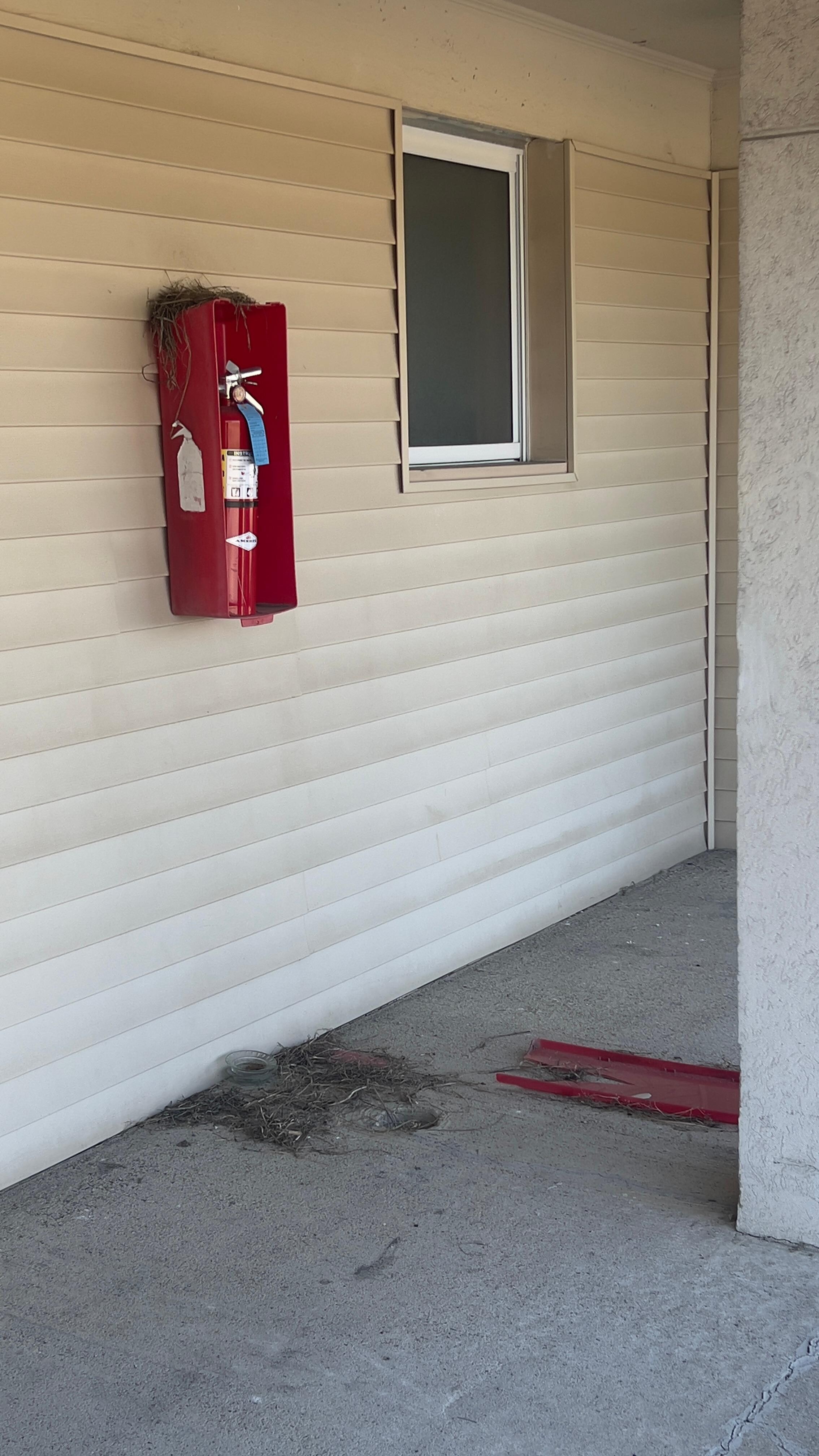 Fire extinguisher cabinet broken, door lying in the walkway.