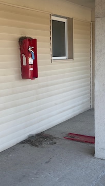 Fire extinguisher cabinet broken, door lying in the walkway.