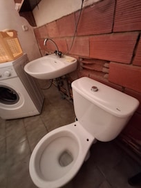 Gäste-WC ohne Klobrille, Trennwand zum angrenzenden Bad unverputzt