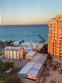 Foto tirada do terraço, que mostra o prédio da frente e a praia