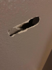 Whole in wall behind the door.