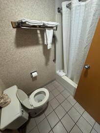 Toilet is small and low , the towel rack or shelf is bent and crooked