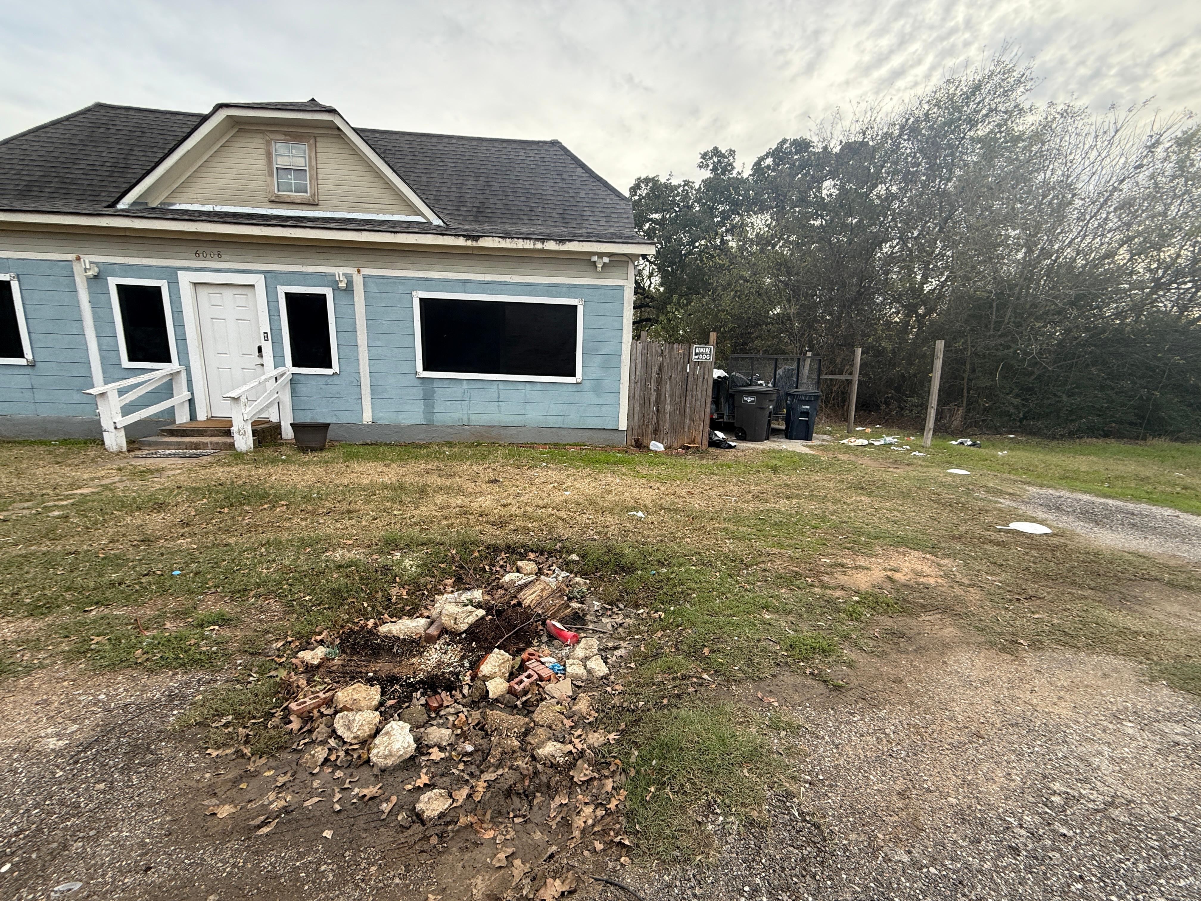 This is the front of the home. The pile of rocks looks like a fire pit in the middle of the “driveway” to the right you can see the broken down car with rubbish all around it. Opposite the home on the other side of the road is highly industrial.