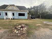 This is the front of the home. The pile of rocks looks like a fire pit in the middle of the “driveway” to the right you can see the broken down car with rubbish all around it. Opposite the home on the other side of the road is highly industrial.