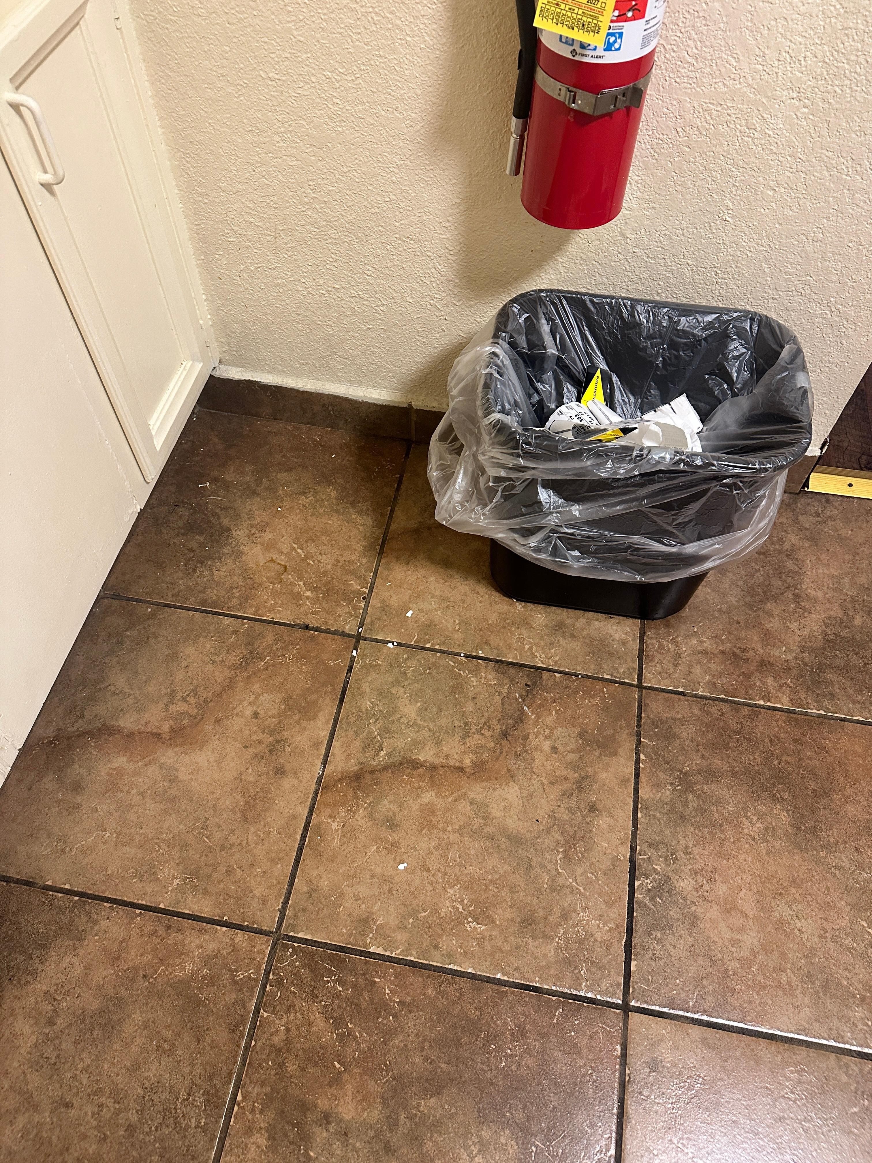 Dirt around waste basket in "cleaned" room.