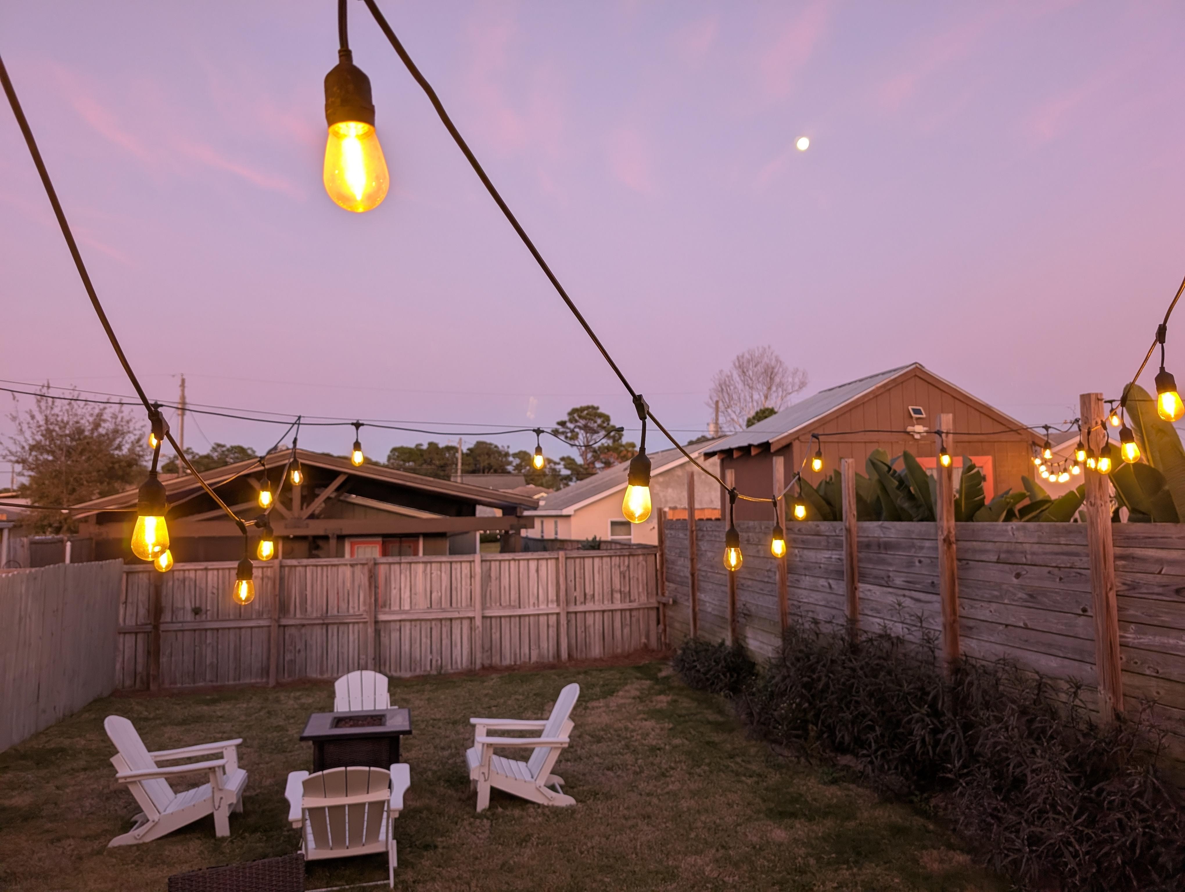 Partial view of Backyard with firepit, lights, and moon in sky. Perfect for stargazing!