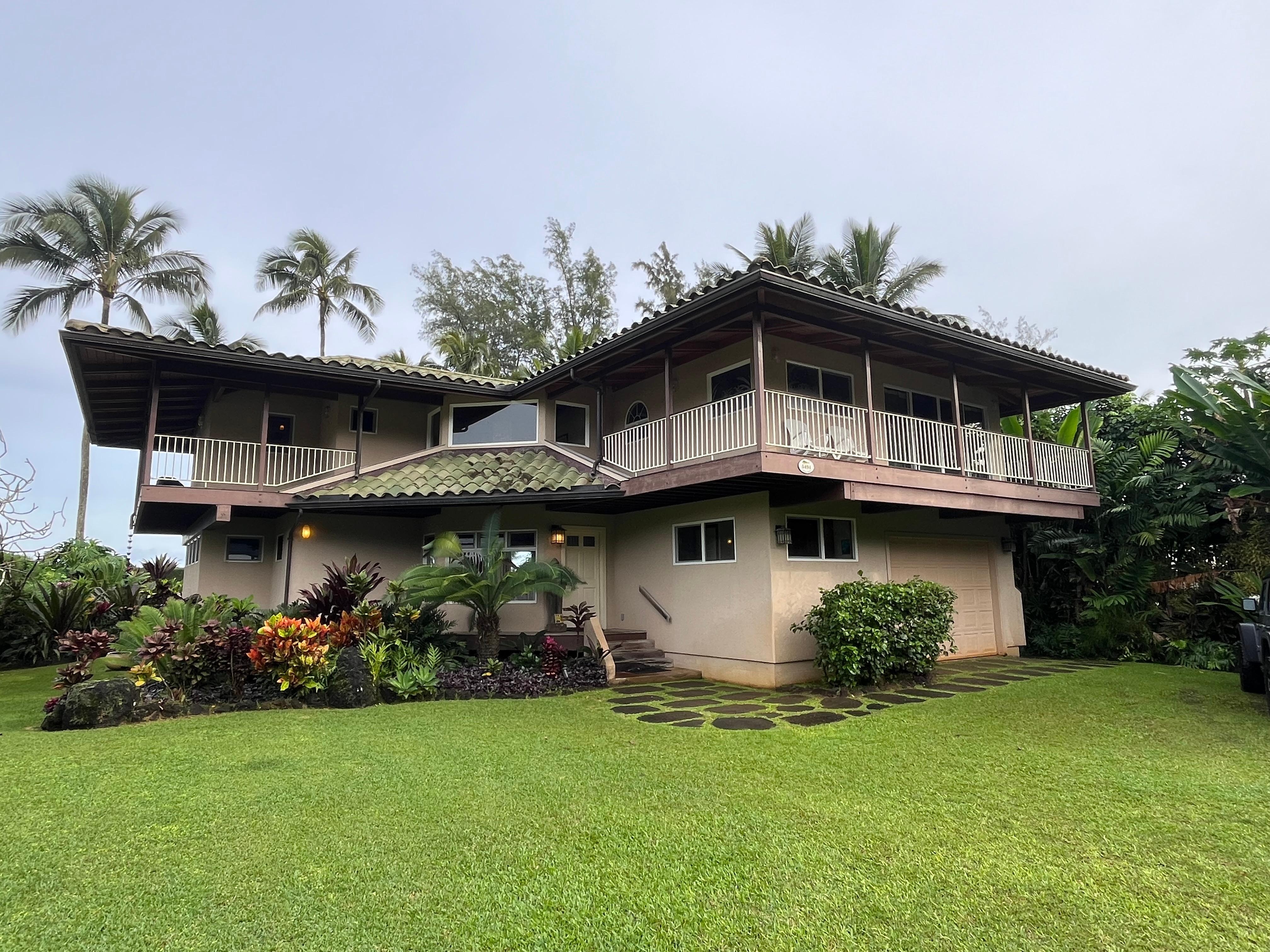 Front of the house, ocean is behind the palm trees