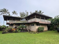 Front of the house, ocean is behind the palm trees
