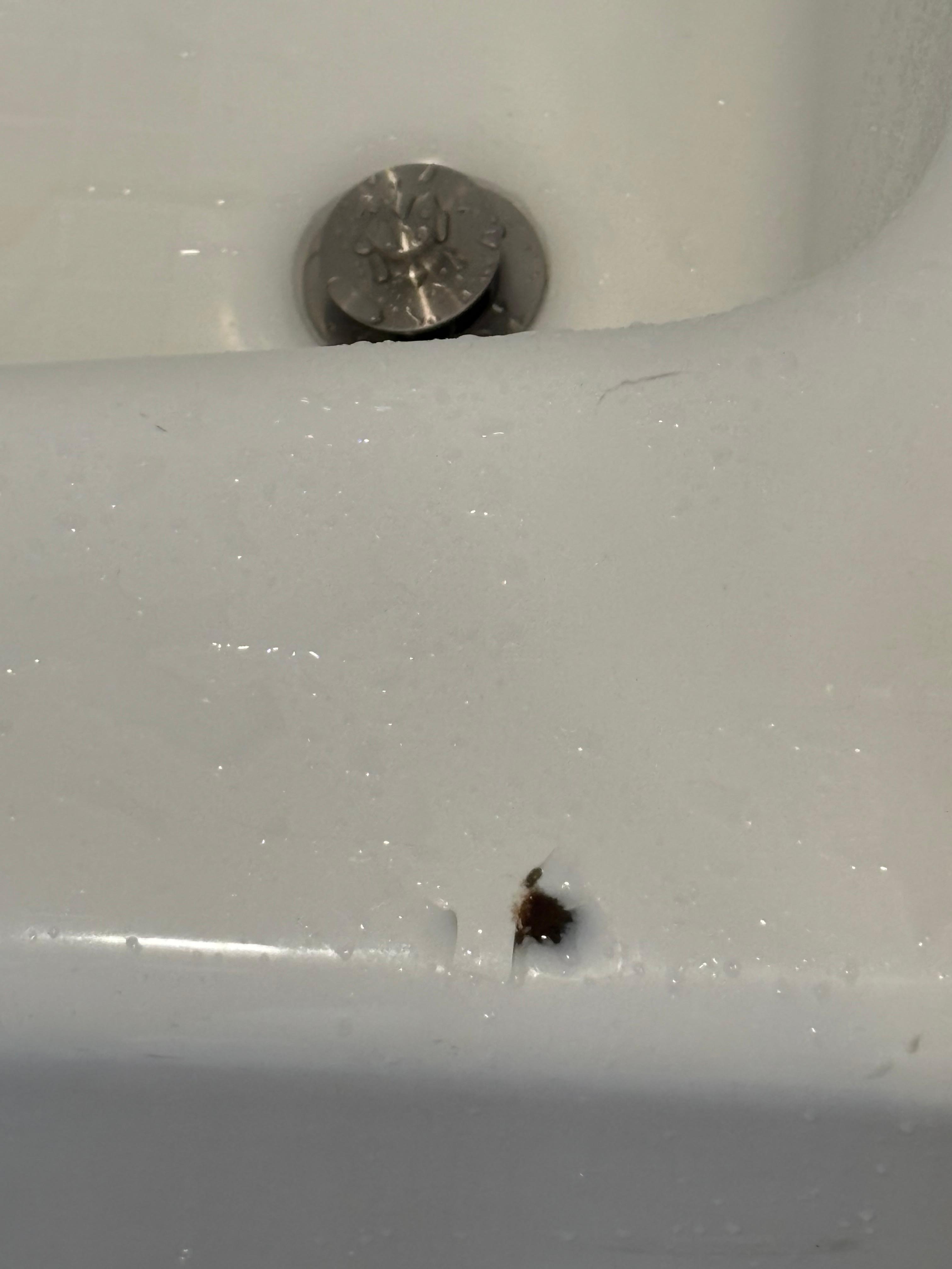 Chip on top of porcelain tub. Sharp like a razor blade