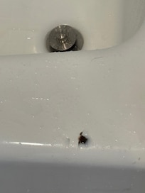 Chip on top of porcelain tub. Sharp like a razor blade