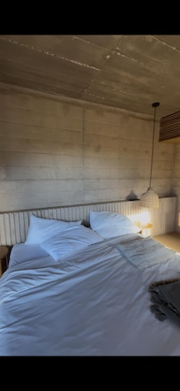 Cama sin hacer, sin sábanas, almohadas sin acomodar e incompletas, sin rack para colocar cortinas y tapar el sol