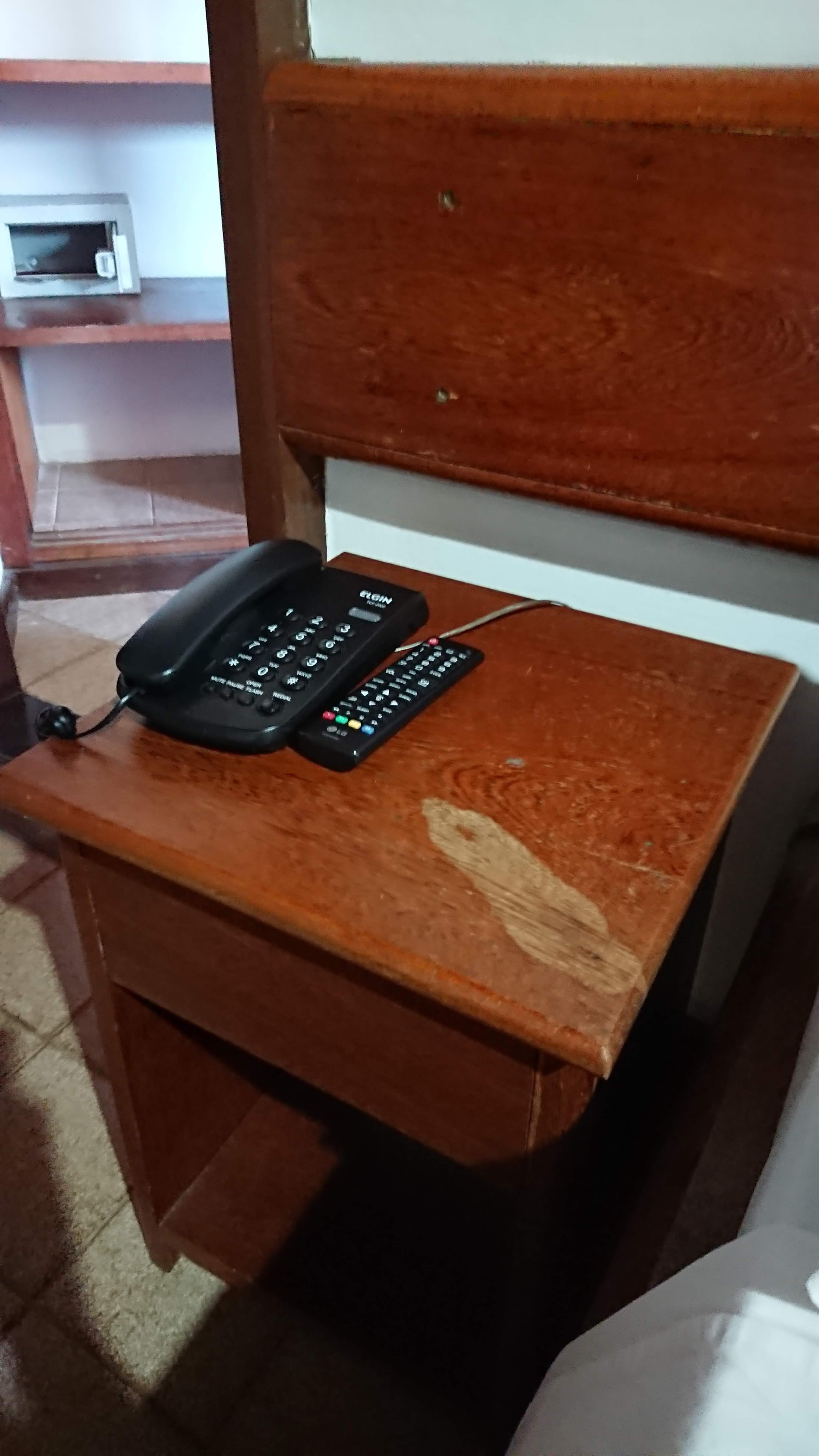 Stained and damaged bedside tables with sticky remote controls.