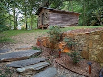 Stone steps and wall with historic looking outbuilding in background.