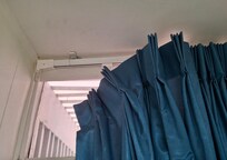 Curtain rod gerry-rigged with a thin piece of wire to hold the drape rod up.