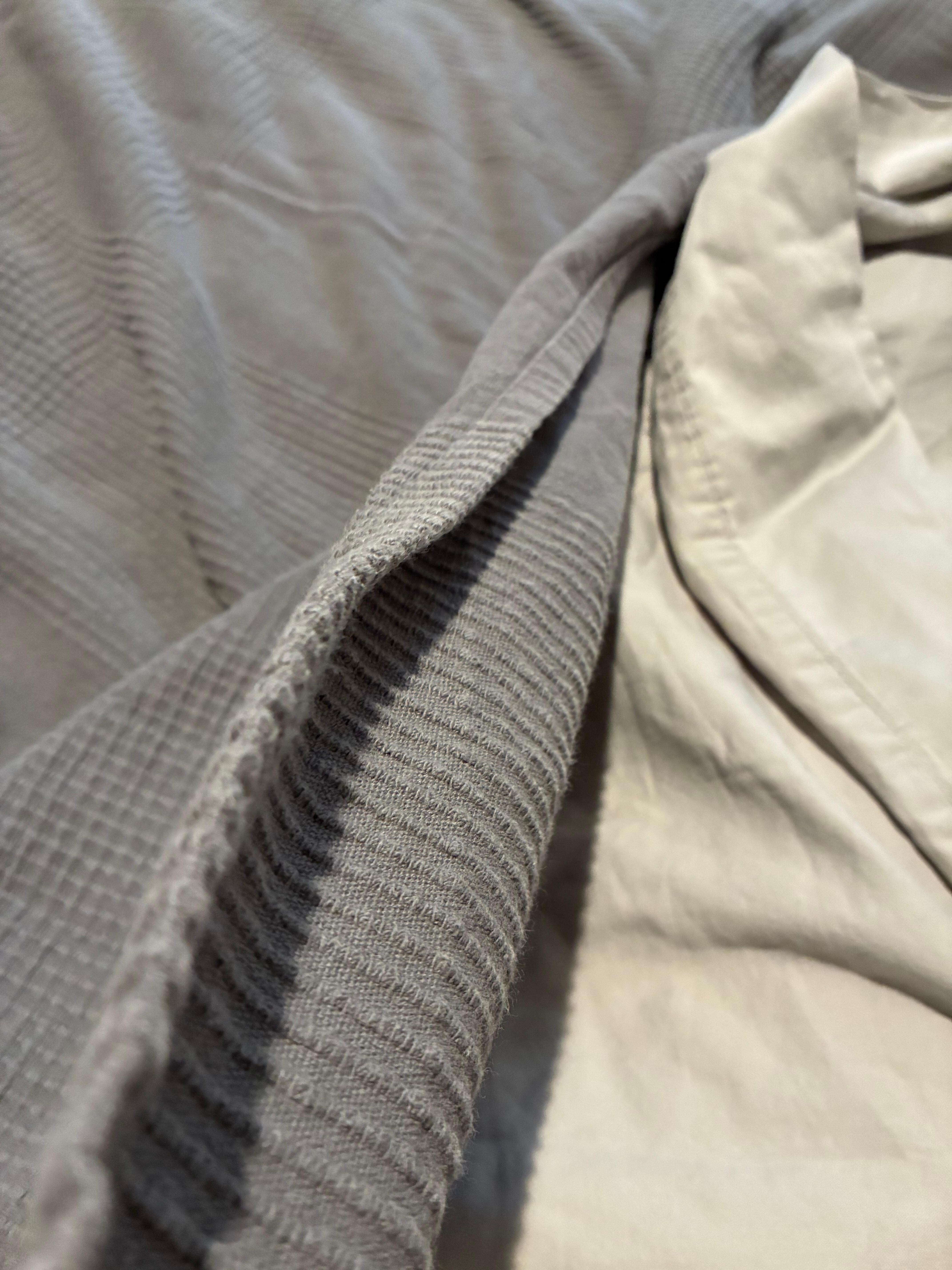 The thickness of the only blanket on the bed.