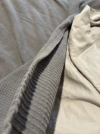 The thickness of the only blanket on the bed.