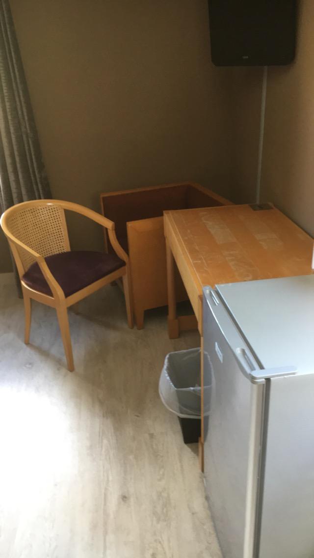 Mobilier de chambre vieillot avec trace devant rond de verre et frigo vide bruyant 