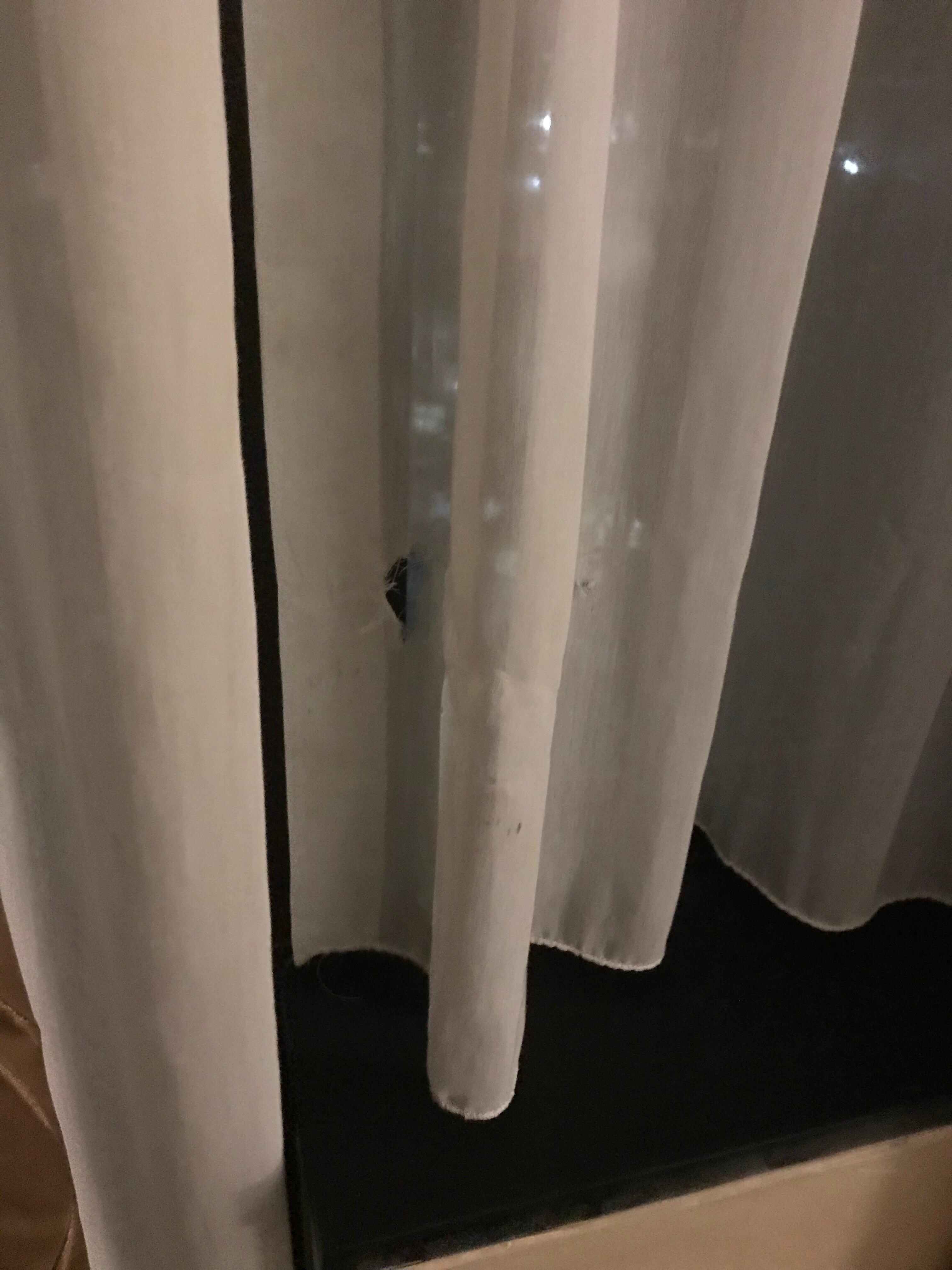 Holes in dirty sheer curtain in bedroom.