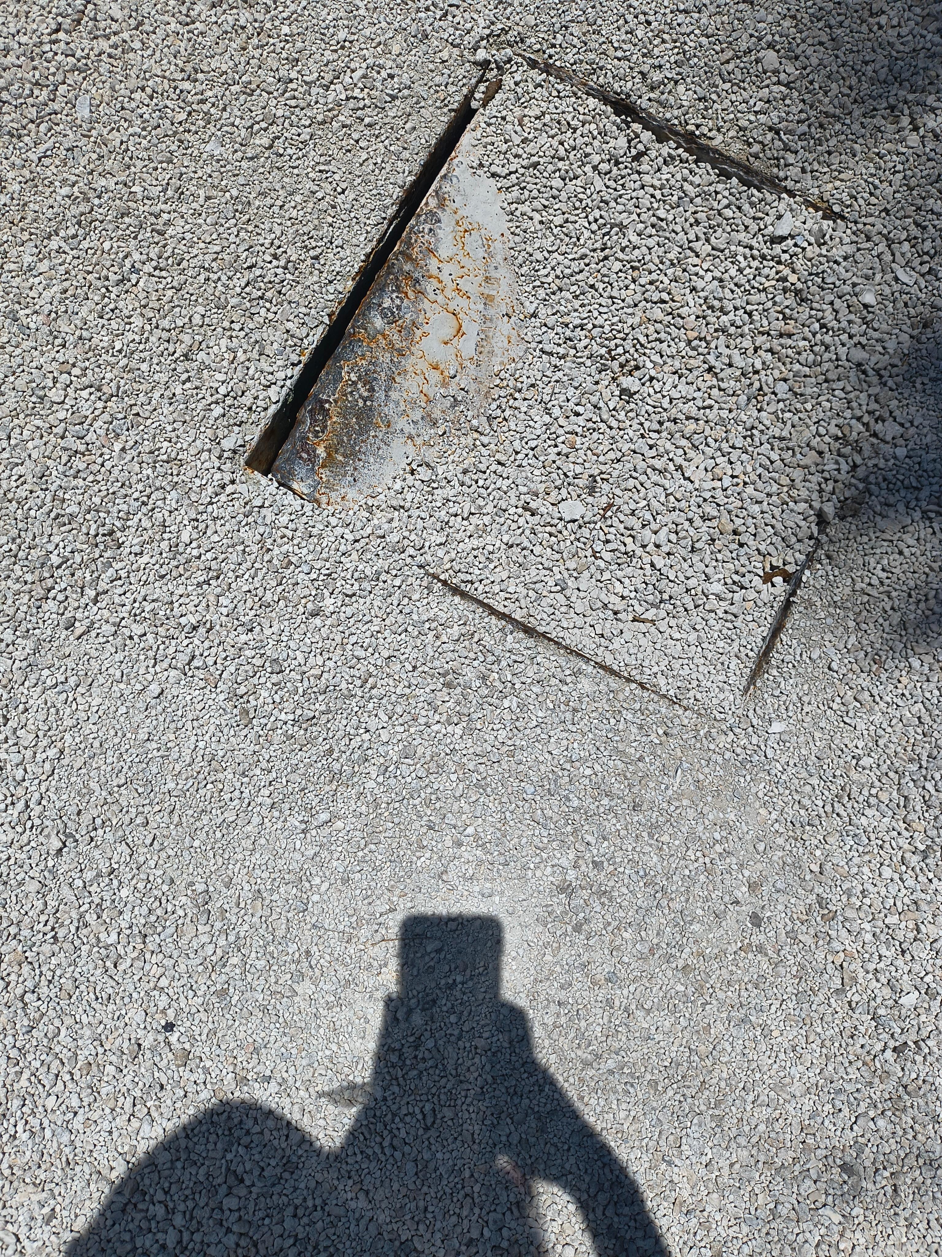 Metal lid between parking spaces #2 & #3. Exposed hole and metal.