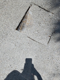 Metal lid between parking spaces #2 & #3. Exposed hole and metal.