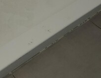 Damage and chunked out caulking and unclean step-in shower