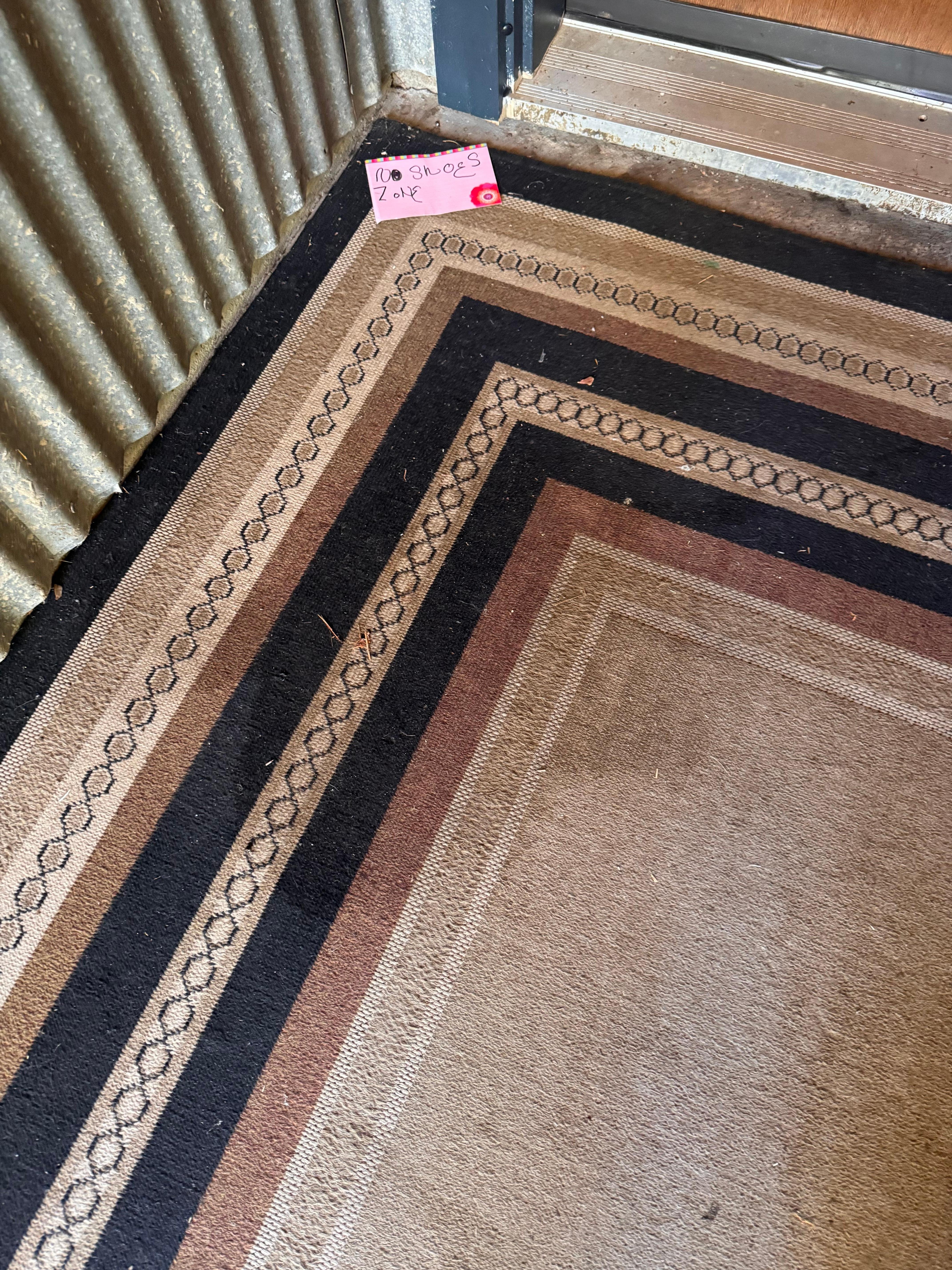 Pee stained carpet at front door next to 'Take your shoes off' hand printed sign!