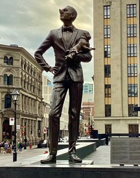Satirical statue of a snooty man holding his pug, the man having a long haughty nose turned up in disapproval of nearby Notre Dame Basilica, in the park near the apt.