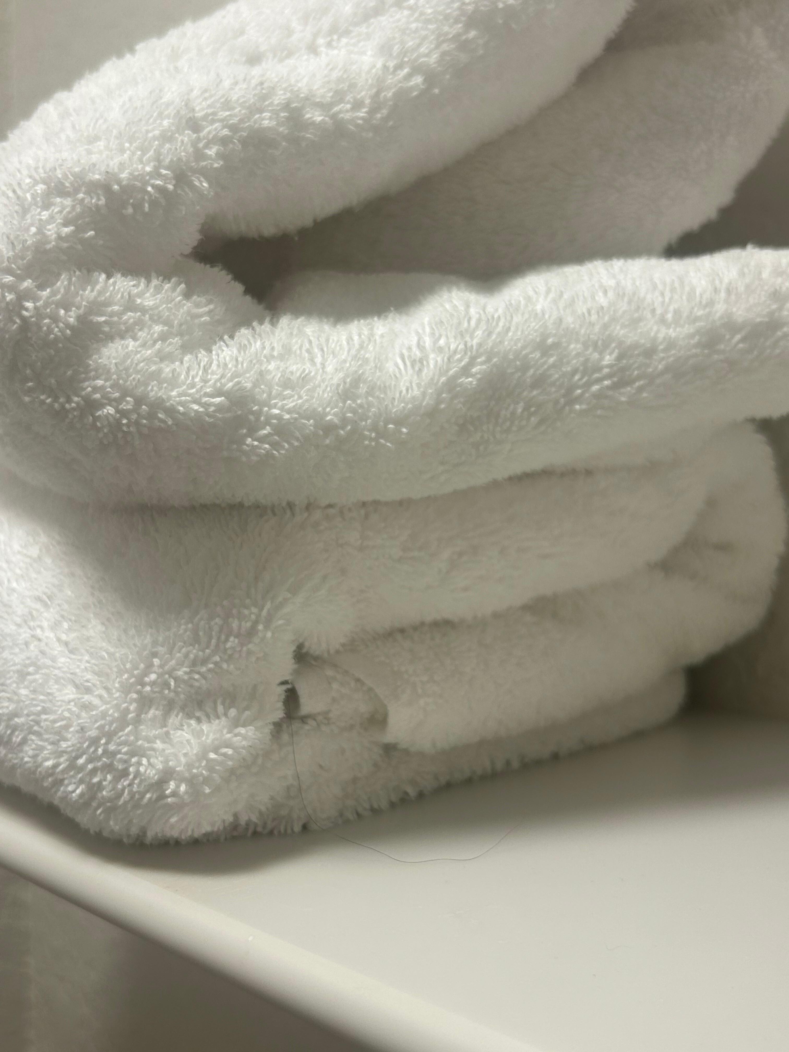 Between the towel folds of the bottom towel there’s a long hair that is stuck between the folds and rests outside of the towel!