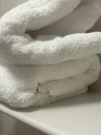 Between the towel folds of the bottom towel there’s a long hair that is stuck between the folds and rests outside of the towel!