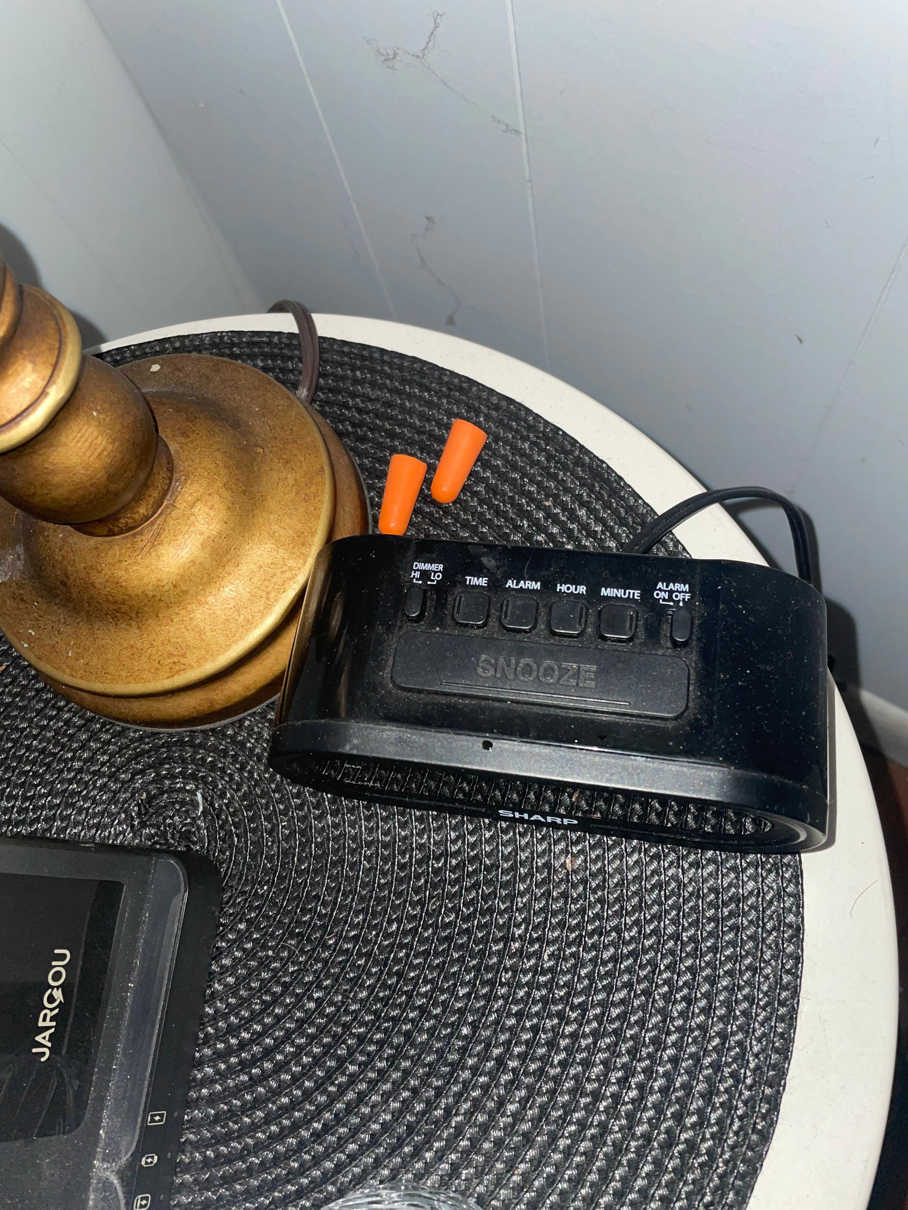 Dirty earplugs on the side of the bed with an unplugged alarm clock